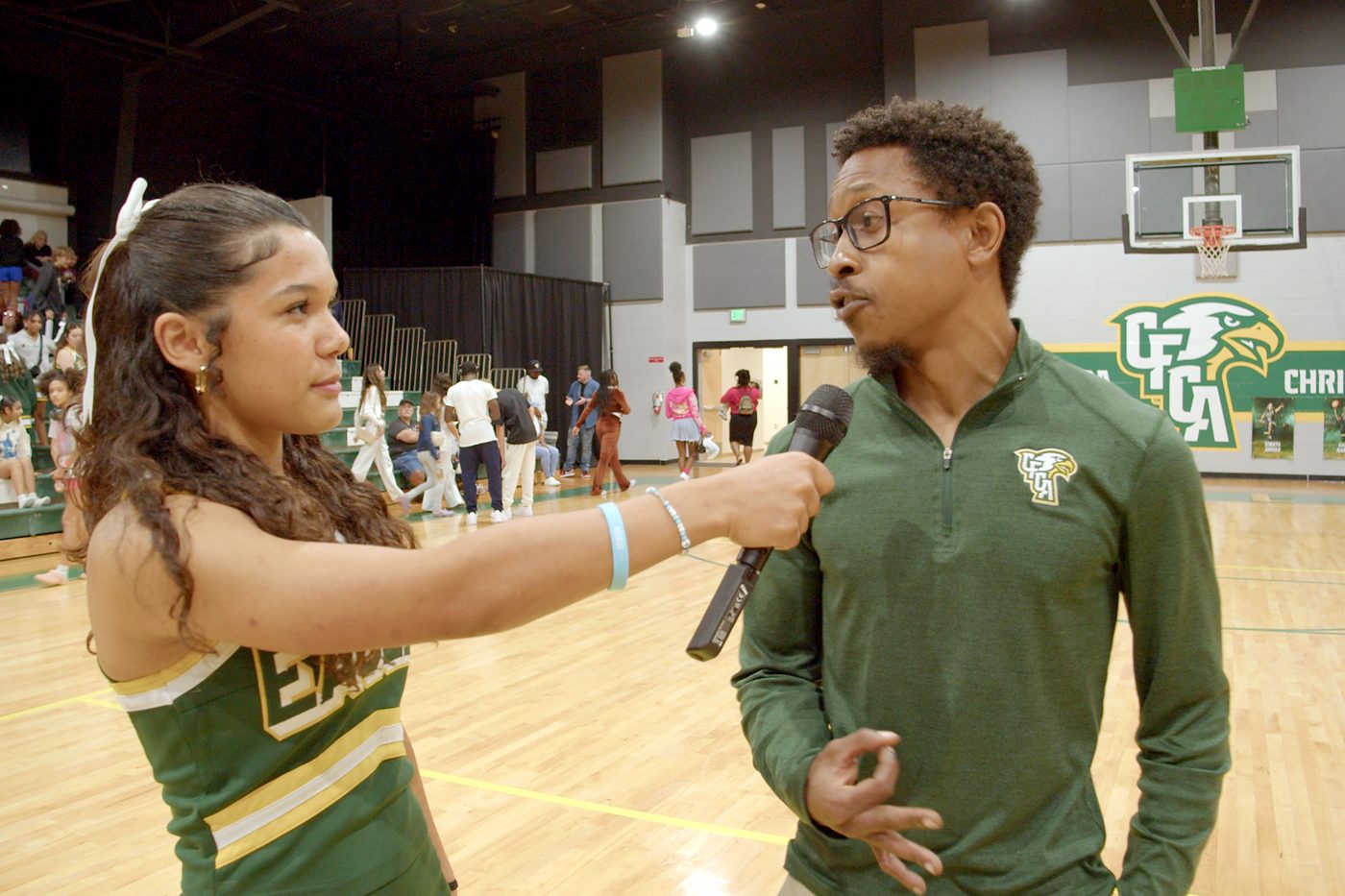 Student interviewing a CFCA athletics staff member on the basketball court.