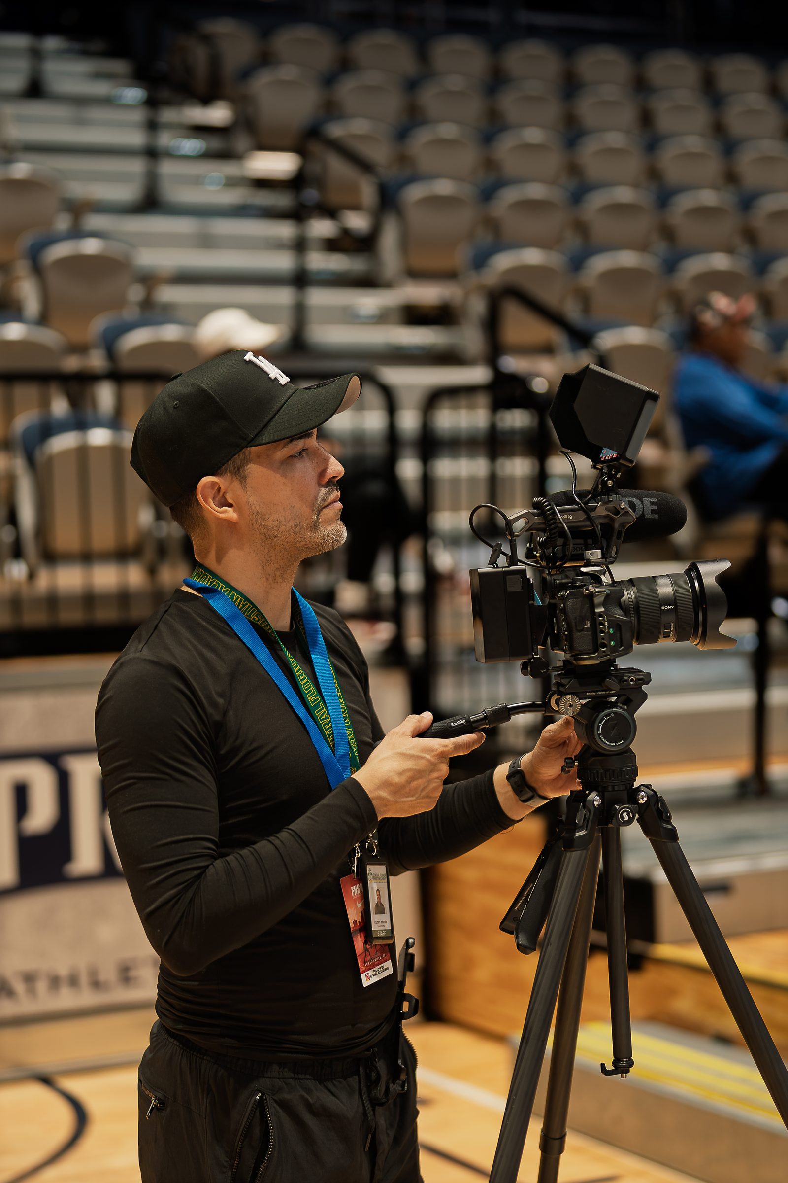 Setting up a camera on a fluid head tripod in a large arena before an event