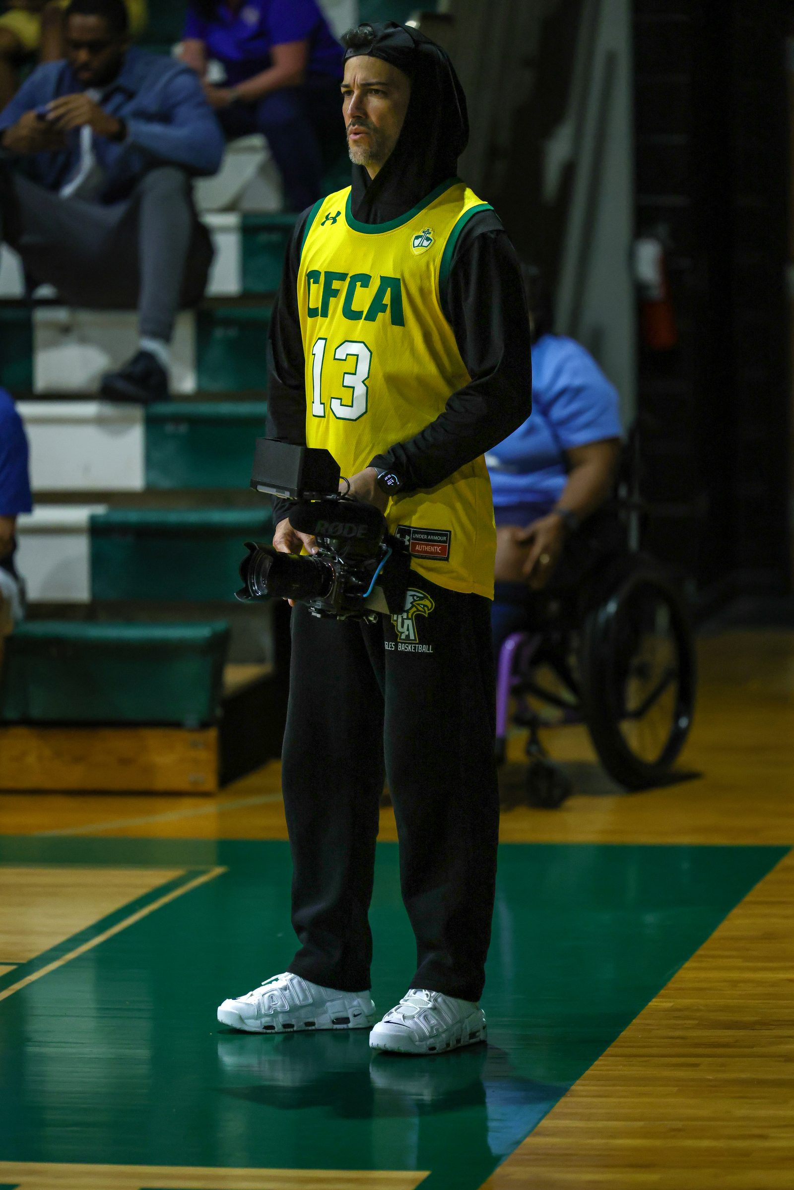 Operating a camera rig at the edge of the court during a game